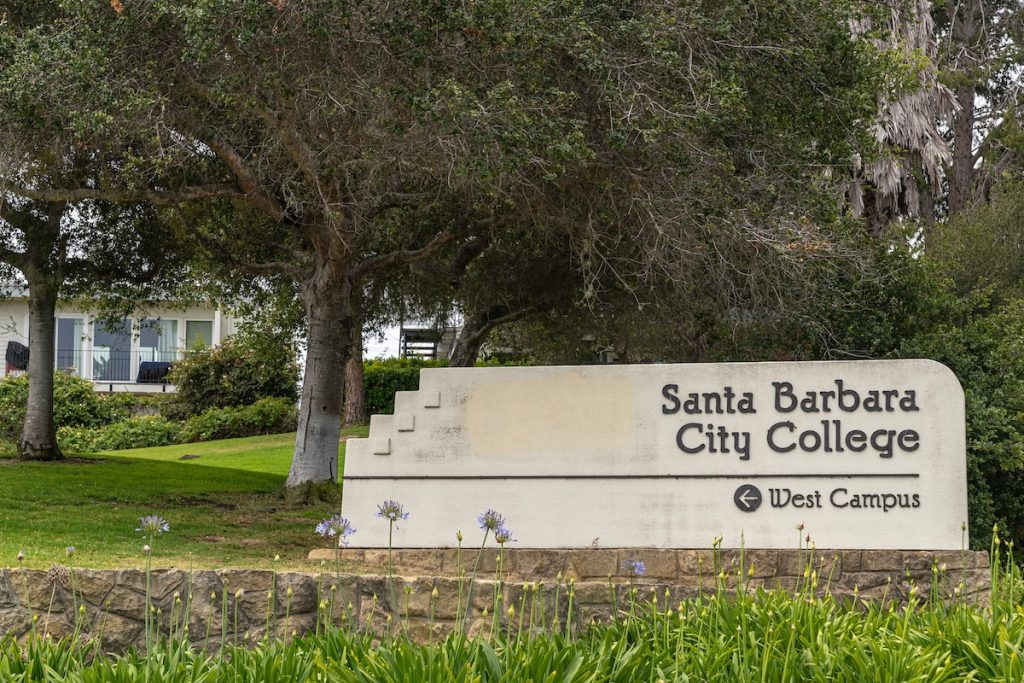 Santa Barbara City College facilities. Closeup, White stone with black name sign set in green garden with tree at entrance to the campus.