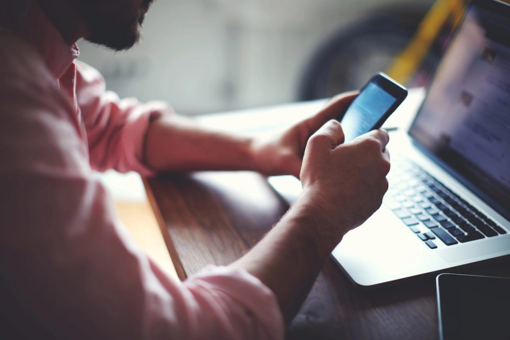 Teen Brokerage vs. UTMA: Key Differences Explained Side view shot of a man's hands using smart phone in interior, rear view of business man hands busy using cell phone at office desk, young male student texting on phone sitting at wooden table