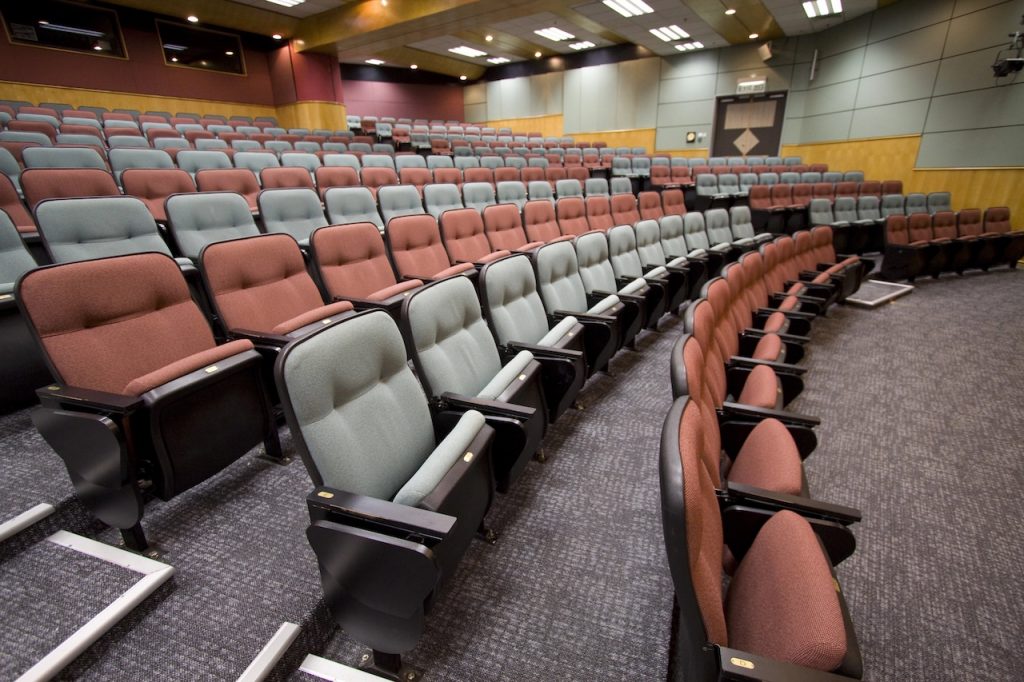 Empty Lecture hall with colorful chairs in a university, reflecting the drop in enrollment due to AI. Source: The College Investor