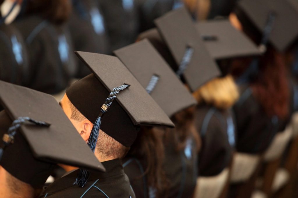 A group of students seated at graduation, highlighting concerns about over educated, under employed.