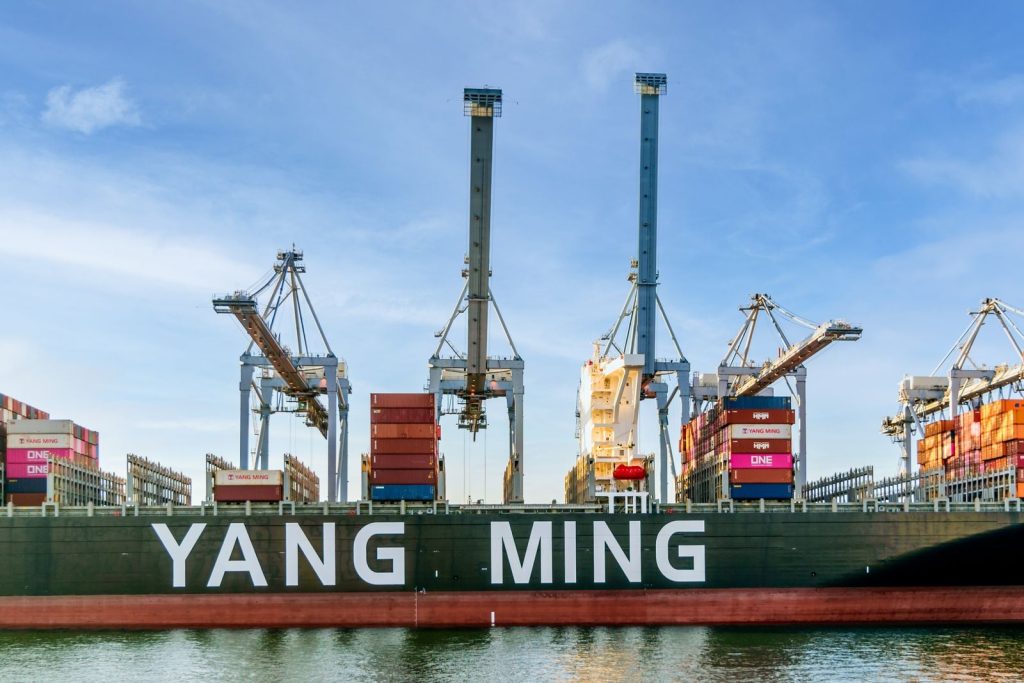 How did a metal box first secured to a converted tanker in April 1956 cut ocean freight loading costs by more than 90 per cent?
